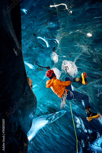 Man climbing frozen ice cave in winter mountains