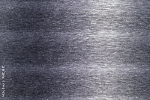 Dark metallic surface displays subtle horizontal brushed texture with varying levels of reflectivity