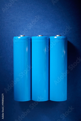 Three blue rechargeable lithium batteries, size 18650, on a blue table.
