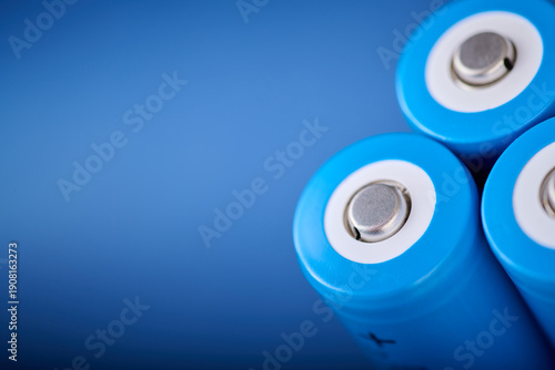 Three blue rechargeable lithium batteries, size 18650, on a blue table.
