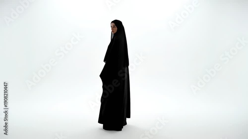 The full-length figure of a muslim woman in a flowing black abaya stands looking over her shoulder, captured in a stark, high-key studio shot against a bright white backdrop.