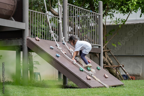 Foto Young child climbing playground structure with rope, outdoor activity for learning and development