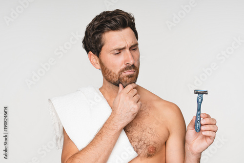 Skincare and pensive man shaving face in studio for wellness, hygiene and cosmetic treatment on white background. Cleaning, beauty and Caucasian model with facial, hair removal and razor blade