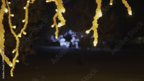 Wallpaper Mural A close-up shot of warm yellow LED light strings hanging vertically in the dark. Glowing blue bokeh orbs create a magical and abstract festive atmosphere for a holiday celebration. Torontodigital.ca