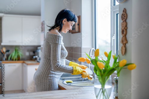 Photos Woman doing dishes in the kitchen while wearing yellow gloves and enjoying the s