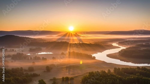 Breathtaking sunrise over misty river valley with sunbeams