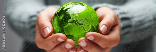 Hands support a green globe representing Earth, highlighting the importance of taking care of the planet during Earth Day activities and events around the world