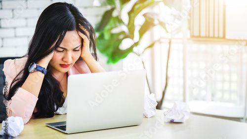 Young Asian woman stress with her frustrated or unsuccessful business online shopping at office. Boring or unhappy business office life concept.