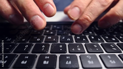 Close-up, wide angle. Low angle view of a Caucasian man's keyboard and hands. Typing text.