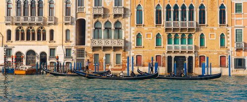 Fotografie Lively Venice canal scene with gondolas, gondoliers and tourists along colorful historic buildings