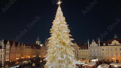 Wallpaper Mural A large, illuminated Christmas tree stands tall in a European city square at night, surrounded by festive market stalls and historic buildings. Torontodigital.ca