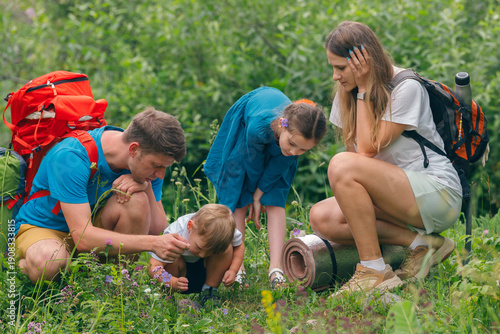Tablou pe pânză A family happily enjoying a picturesque nature hike, discovering various plants