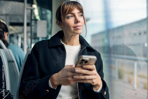 Focused entrepreneur using mobile on public transport window seat
