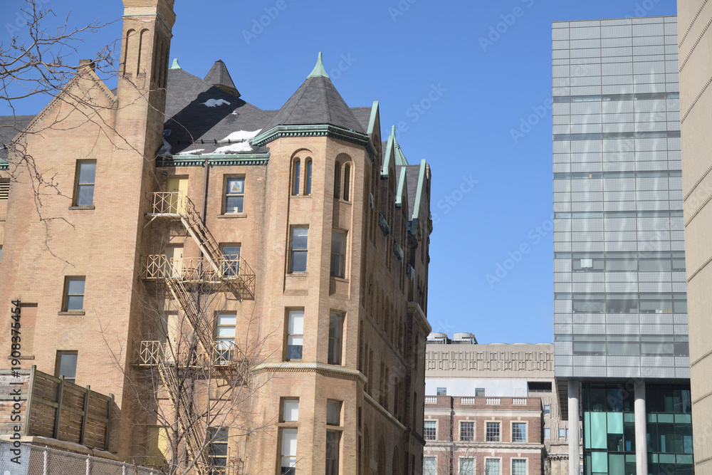 Fototapeta premium contrast of architectural styles: (left) Stewart Building designed by Edward James Lennox, completed 1894, in Richardsonian Romanesque, located at 149 College St, Toronto