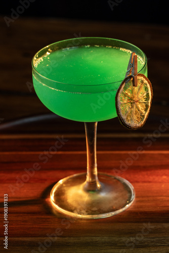Green edible glitter used to garnish a drink on a wooden surface lit with a high key light and shadows