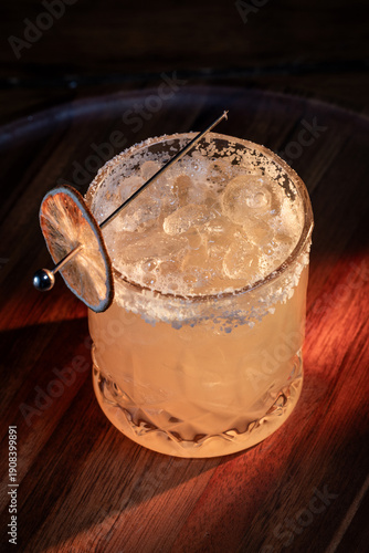 close up of a salted rim margarita with a dehydrated lime wheel garnish on a dark background