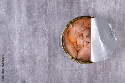 Canned cod liver in open metal tin with oil on the gray table. Copy space, top view