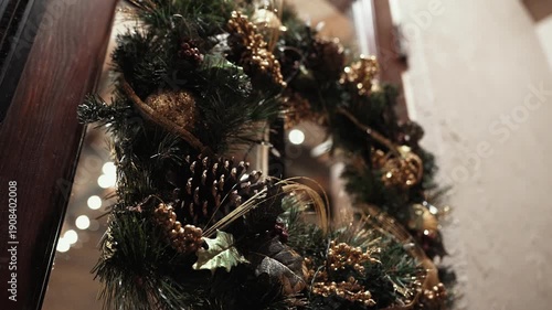 A Christmas wreath with fir, pinecones, and other holiday decorations hangs from a front door.