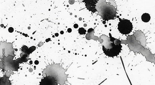 Artistic black ink splashes, droplets, and splatters on a clean white paper background. Abstract messy paint texture