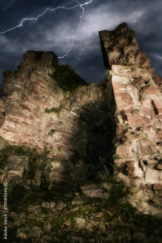 Fototapeta premium Old ruin at night with dramatic sky. A moody mystical fantasy scene with real castle walls and stormy sky with lightning.