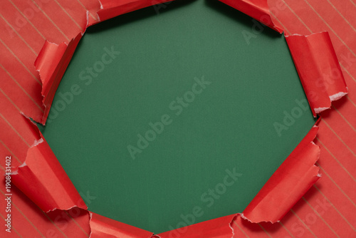 Torn red wrapping paper revealing a green background during holiday gift preparation