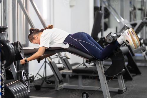 Quadro su tela Woman exercising hamstrings on leg curl machine in a gym