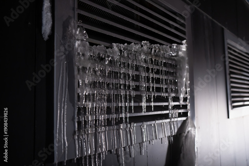 Konstfotografi Air conditioner outdoor unit covered with thick ice buildup and icicles on metal