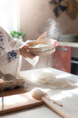 Flour pouring, sifting in sunlight in cozy home kitchen. Slow cooking, mindful homemade Easter baking. Close-up of child hands. Authentic candid lifestyle moment. Grandmacore traditions, hygge
