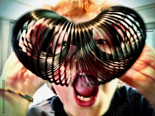 Photos Playful portrait with face framed by coiled metal spring toy