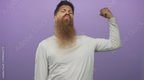 Man flexes bicep muscle in studio with index finger pointing to peak and clenched fist and determined expression; confidence.