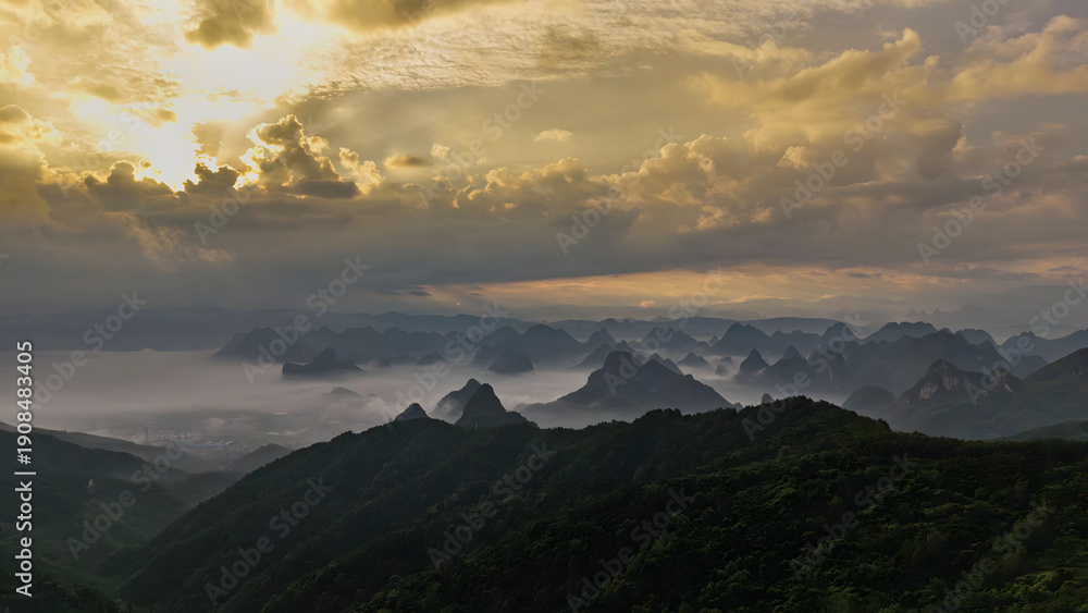 Obraz premium Guilin Mountains at Golden Hour with Misty Peaks and Dramatic Sky