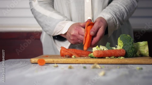Hand peeling raw carrots with brocolli
