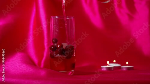 Serving of fizzy red ripe cranberry juice on pink valentine background