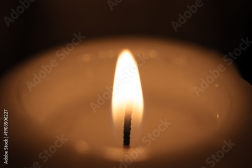 The wick of a burning wide candle in a church