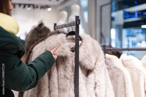 Woman touching a faux fur coat in a clothing store.
