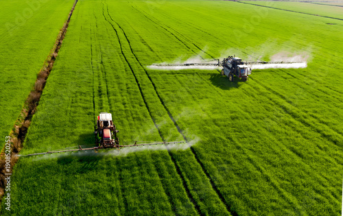 Foto Agricultural Sprayers Applying Fertilizer to Green Wheat Fields