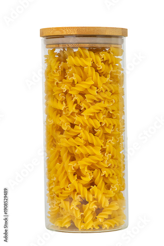 Glass jar filled with uncooked fusilli pasta on a white background