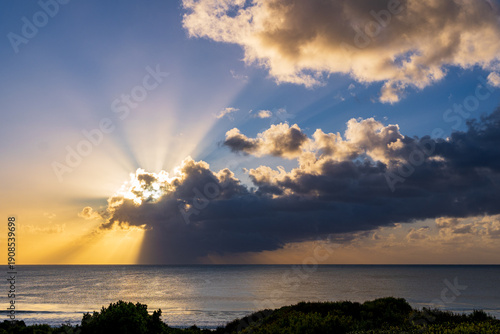 Canvas Print Dramatic ocean sunrise with crepuscular sun rays breaking through clouds over a