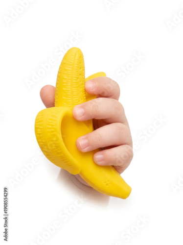 Close-up of a child's hand holding a bright yellow banana-shaped teether against a white background