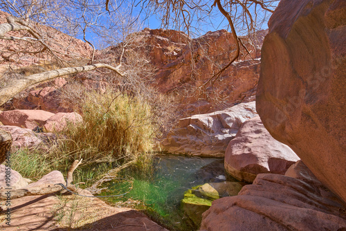 A permanent water pool Galt el Azraq between granite rose-colored rocks in highlands of Sinai, Egypt. Turquoise water of the pool. Vacation and hiking in the national park Saint Katherine Protectorate