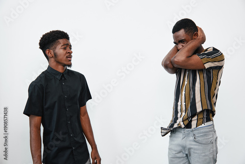 Фотография Two young black men with dark skin in casual clothes having a tense conversation in studio