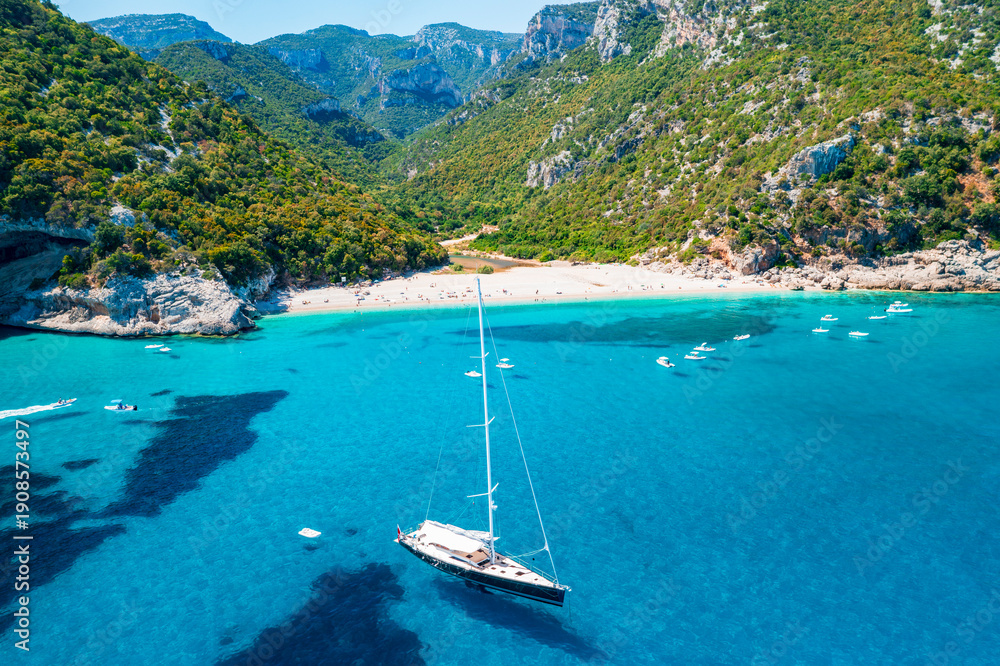 Obraz premium Aerial view of Cala Sisine, beautiful sandy beach with tourquoise water and limestone mountains along the Baunei Coast, Gulf of Orosei, Sardinia, Italy