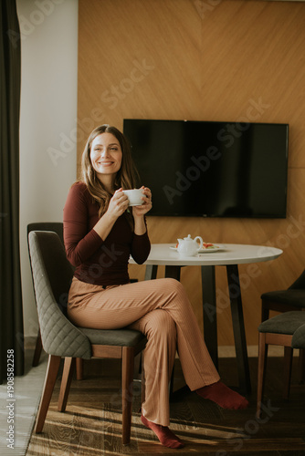 Woman sits at table holding...