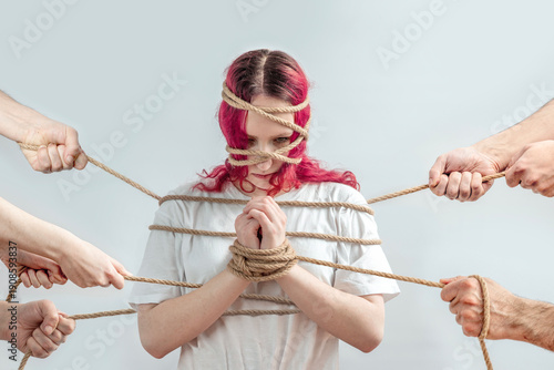 Εκτύπωση καμβά Teen girl tied with rope and pulled from different sides by hands, concept of domestic abuse, hostage and violence threat, loss of autonomy, fear, trauma and mental health crisis