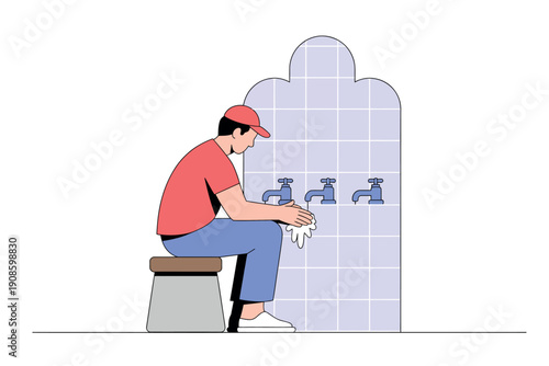 A man in a red shirt and cap sits on a stool wiping his hands under a row of public sinks