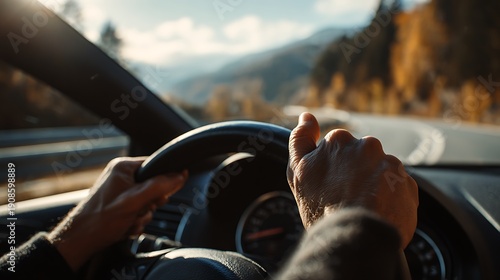 Close-up of senior hands on a steering wheel driving a car on a scenic mountain road during a sunny autumn day