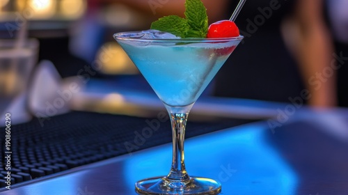 A vibrant blue cocktail adorned with a cherry, fresh mint, and ice, embodies refreshing summer vibes and joyful celebrations, inviting relaxation and enjoyment by the bar.