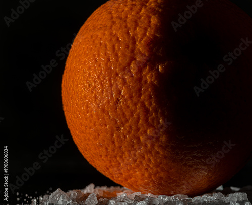 Orange fruit detail with shiny black table and white salt