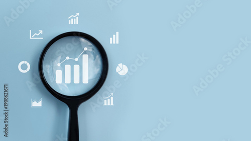 Magnifying glass analyzing business growth charts and data icons, representing analytics, performance tracking, financial analysis, and strategic planning.