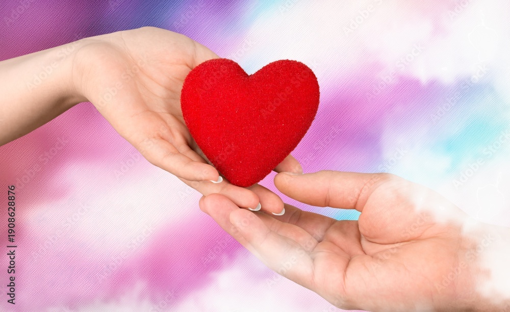 Fototapeta premium People hands holding red heart on pink background.